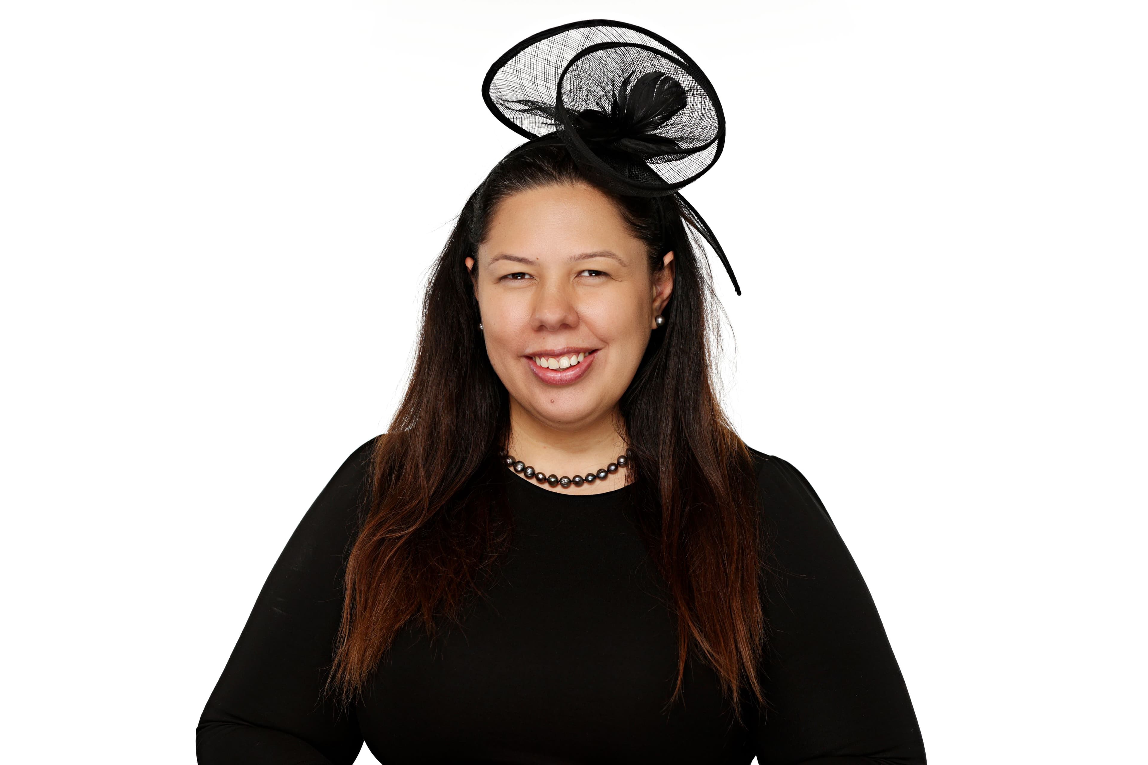 Rubina Carlson, smiling, in a black top and black fascinator.